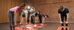 Fitness group performing exercises with dumbbells in a modern yoga studio setting.